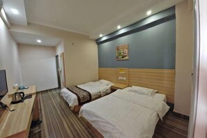 Une chambre d’hôtel avec deux lits, un bureau avec un ordinateur et une télévision.