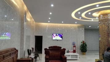 A lobby with a TV, seating area, and a decorative column.