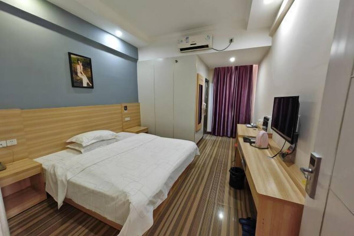 Habitación de hotel con cama, escritorio, televisor y aire acondicionado.