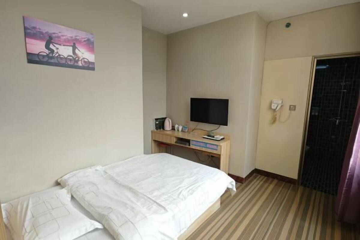 Habitación de hotel con cama, escritorio con televisor de pantalla plana, un cuadro en la pared y una puerta.