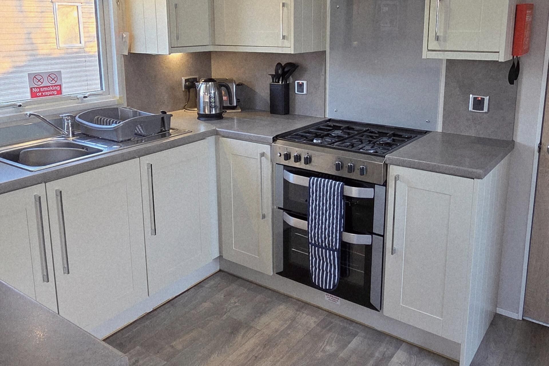 A compact kitchen with a gas stove, oven, and a coffee maker.
