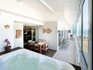 A modern interior with a dining area, a hot tub, and a view of the sea.