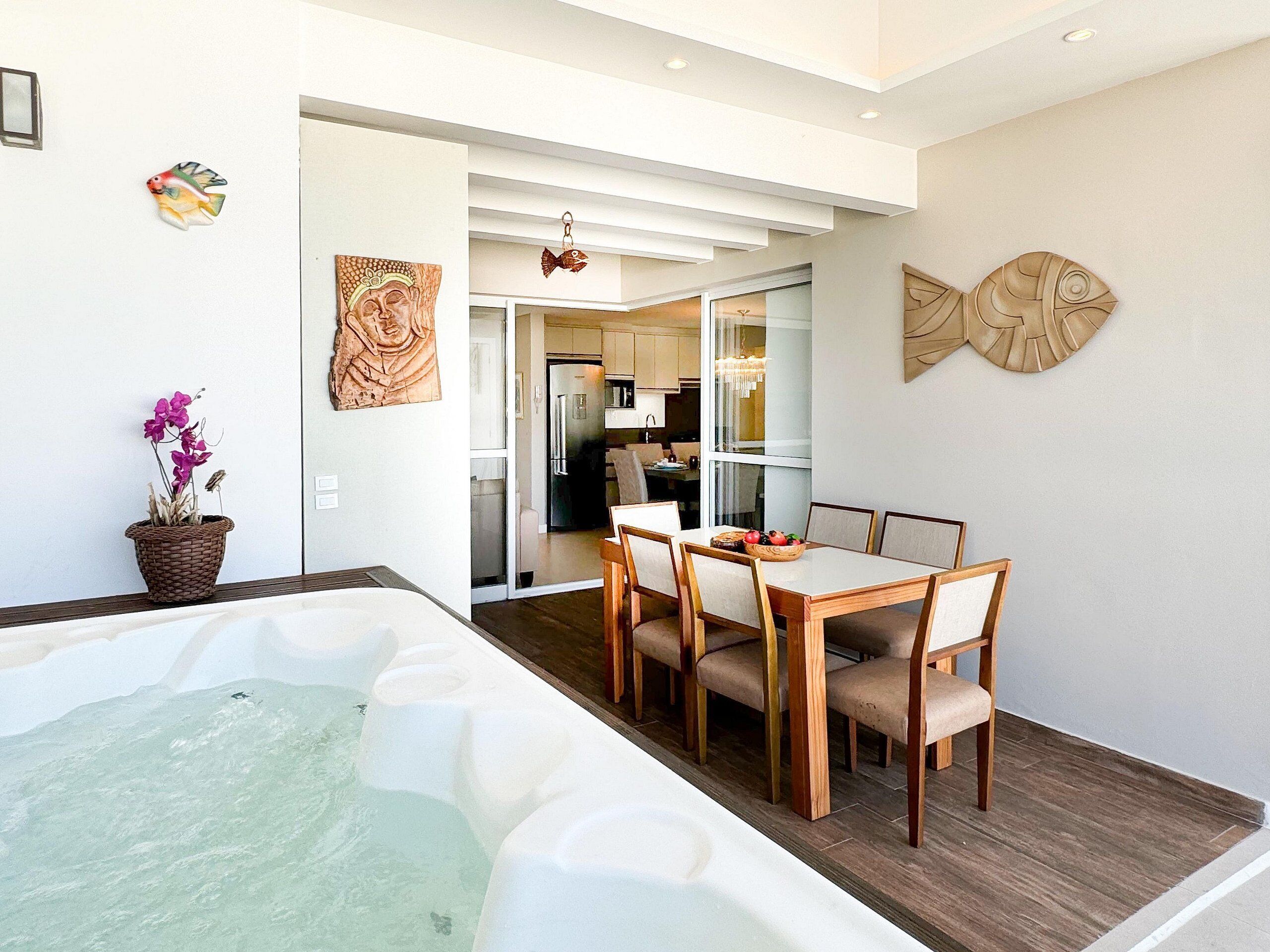 Un interior moderno con jacuzzi, comedor, cocina y obras de arte.