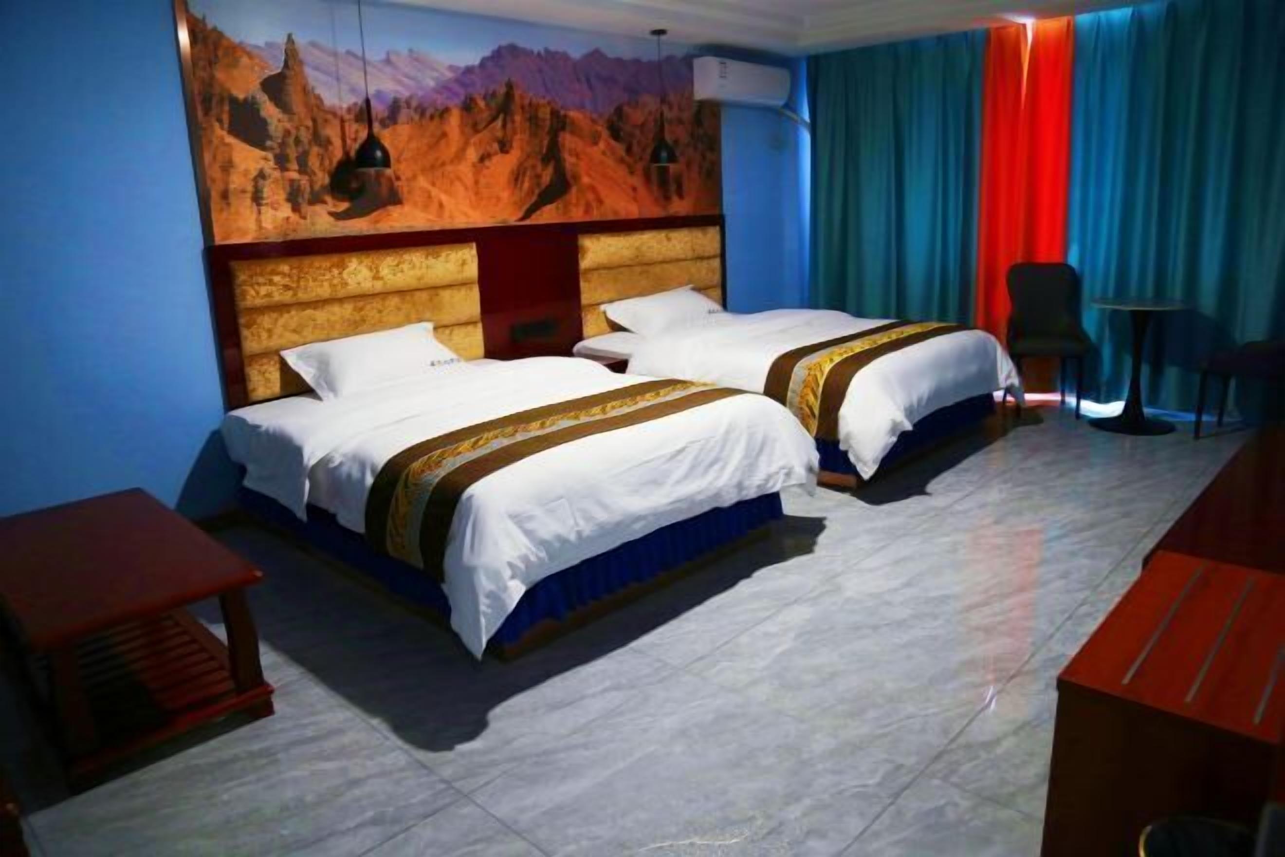 Habitación de hotel con dos camas, cabecero de madera, un mural en la pared y vistas a las montañas.