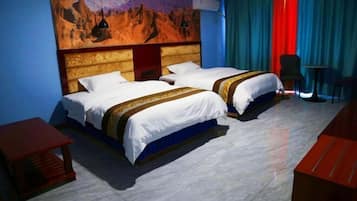Habitación de hotel con dos camas, cabecero de madera, un mural en la pared y vistas a las montañas.