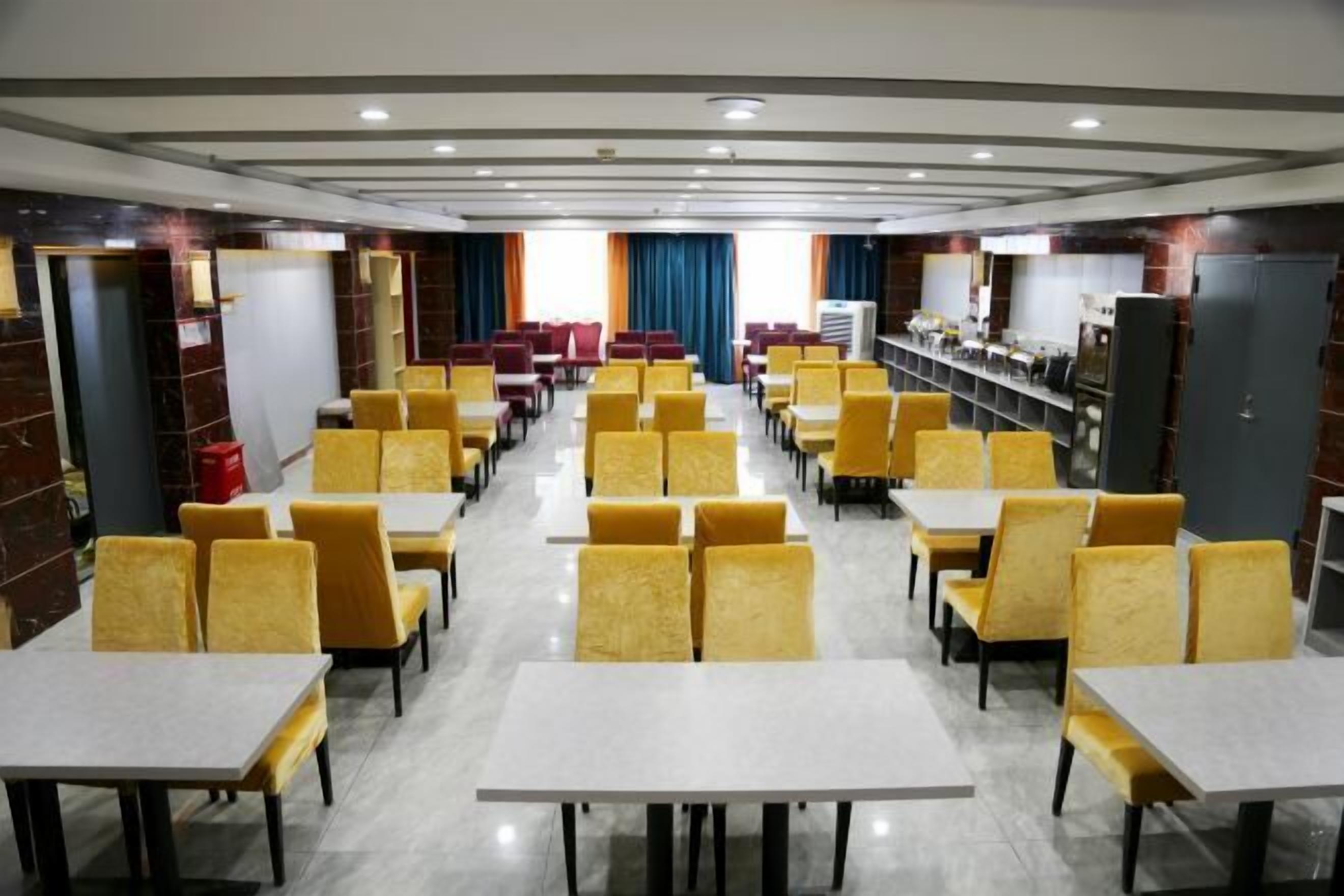 A spacious dining area with yellow chairs and white tables, arranged in rows.