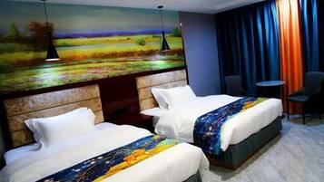 Een hotelkamer met twee bedden, een landschapsschilderij, een tafeltje en een stoel.