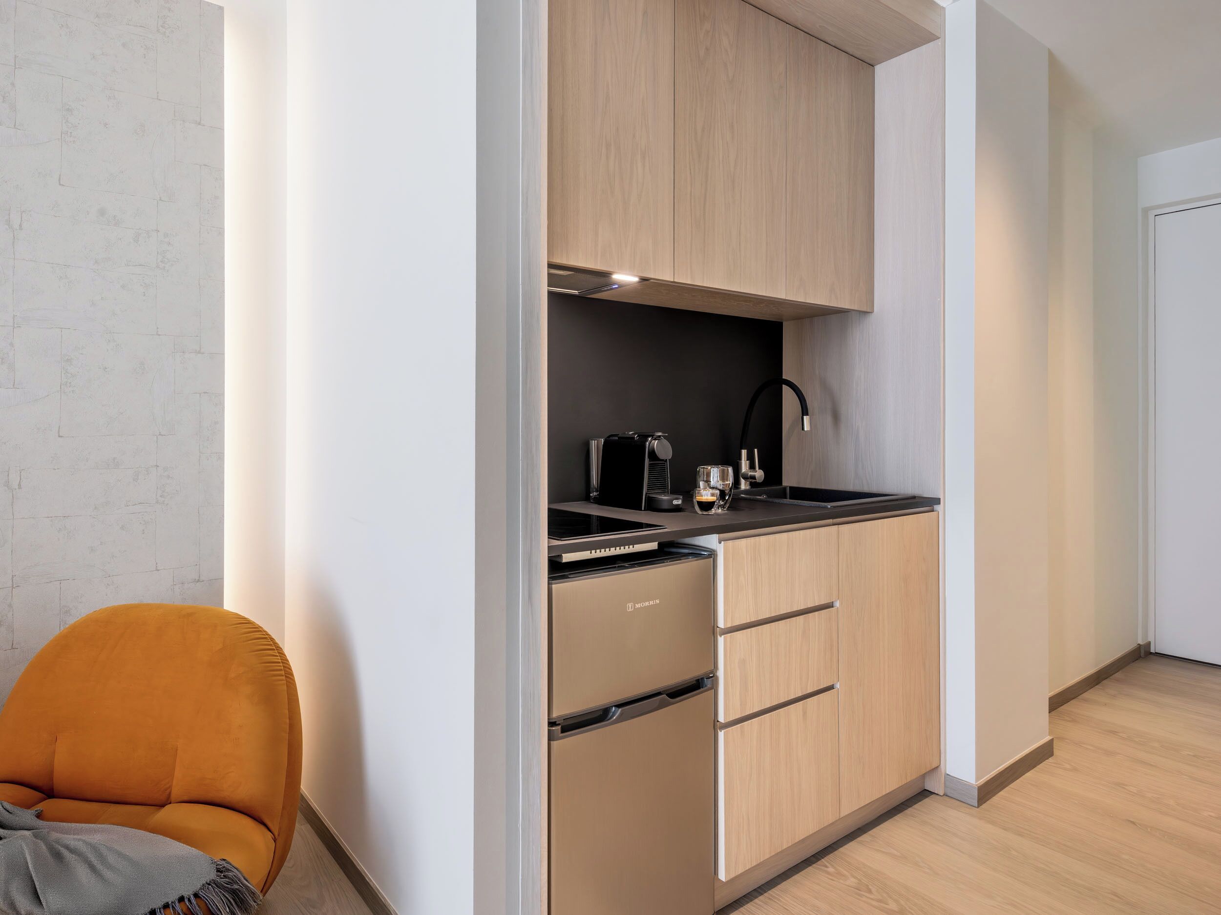 A compact kitchen with a built-in stove, a coffee maker, and a sink.