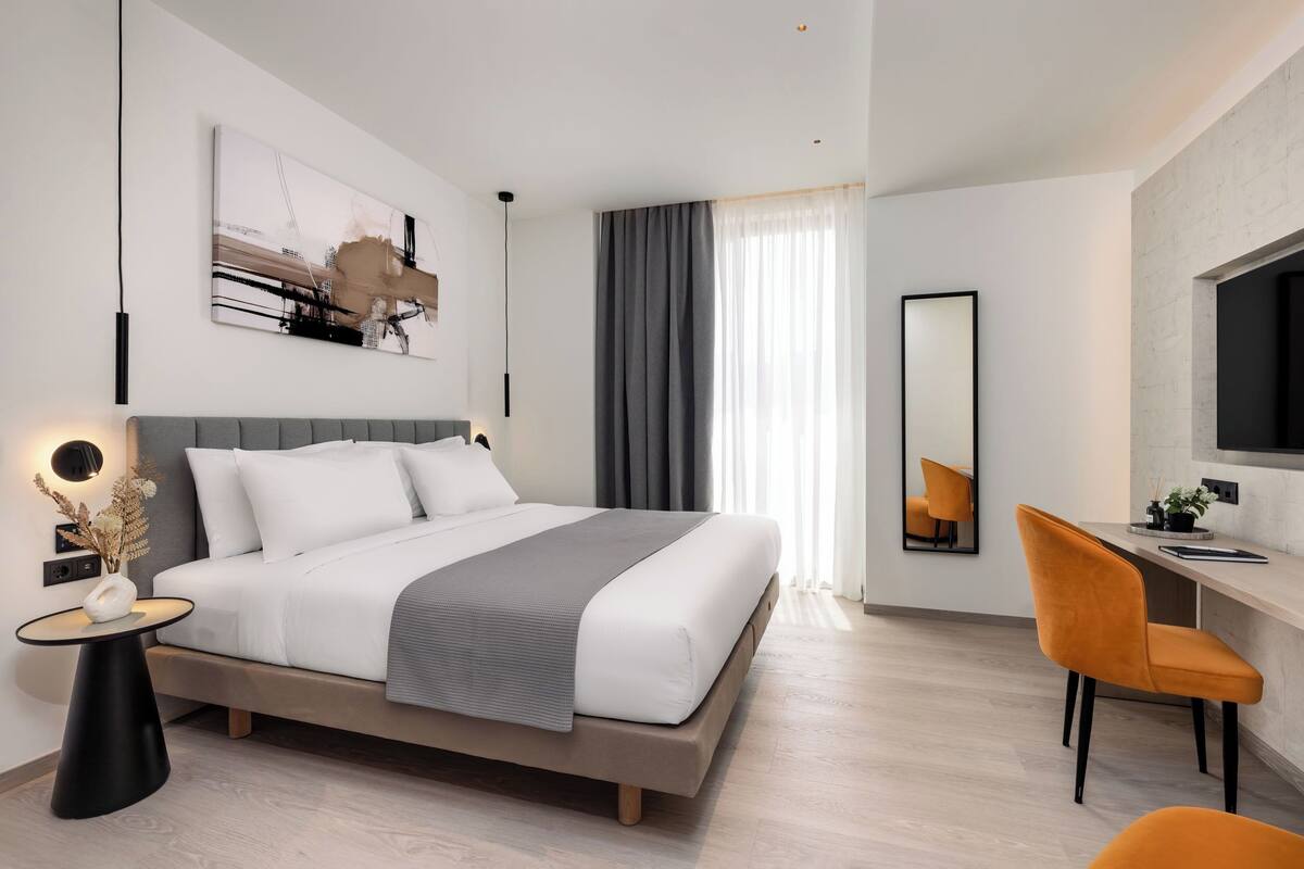 A modern bedroom with a bed, bedside table, and a desk with a chair.