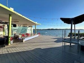 A wooden deck with outdoor seating, a covered area, and a view of the water.