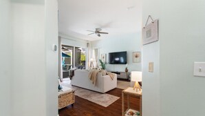 Een moderne woonkamer met een witte bank, een flatscreen-televisie en een plafondventilator.