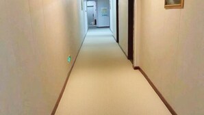 A narrow hallway with a carpeted floor and plain walls.