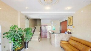 A spacious living area with a staircase, a reception desk, and a leather sofa.
