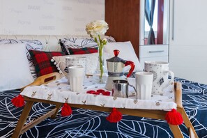 A neatly arranged breakfast tray on a bed with a floral-patterned bedspread, a vase with a white flower, and a coffee pot. - Charming Apartment in Zadar With City Views (Zadar)