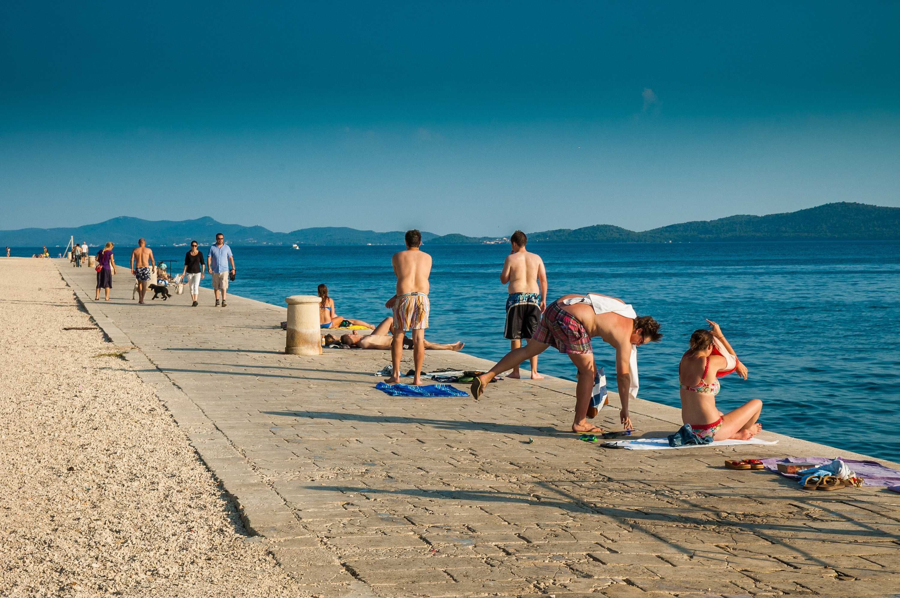 Een strand met mensen die zonnebaden en over het strand wandelen.