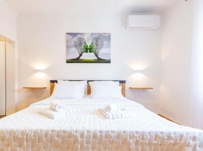 A neatly made bed with white linens and towels, a headboard, and two wall-mounted lamps. - Peaceful Murvica Villa Pool, Garden, and Modern Comfort (Policnik)