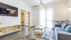Una sala de estar moderna con un sofá, una mesa de centro y un televisor montado en la pared.