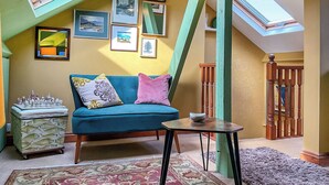 A cozy loft with a blue sofa, a small table, and a fish-patterned chest of drawers.