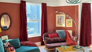 A living room with teal sofas, a coffee table, and a red sofa with a blue throw.