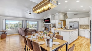 A spacious living area with a fireplace, dining table, and kitchen. - Temecula Wine Country Home w/ Pool, Hot Tub, Game Room & Vineyard Views (Temecula)