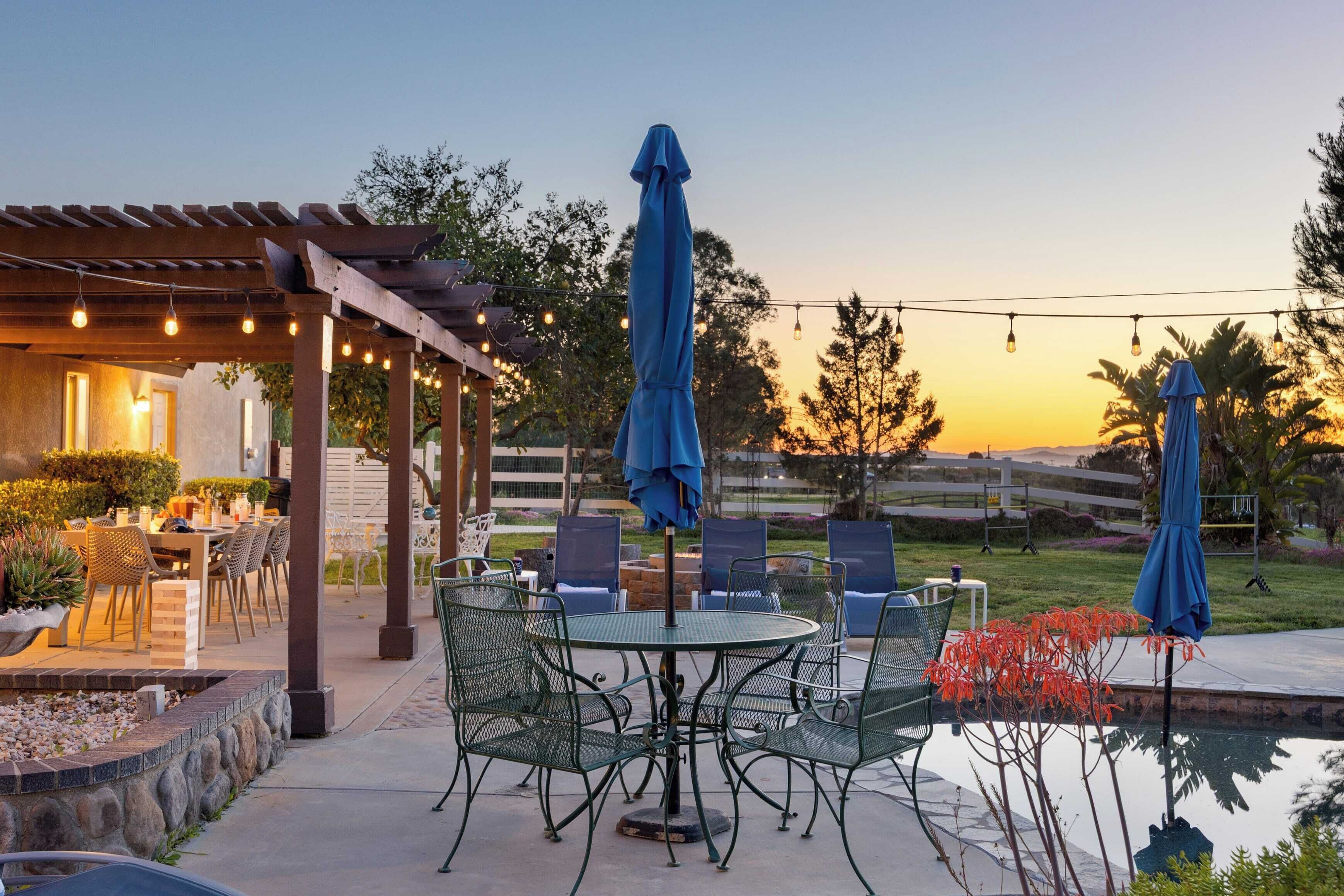 Une terrasse extérieure avec une piscine, un espace repas et des parasols.