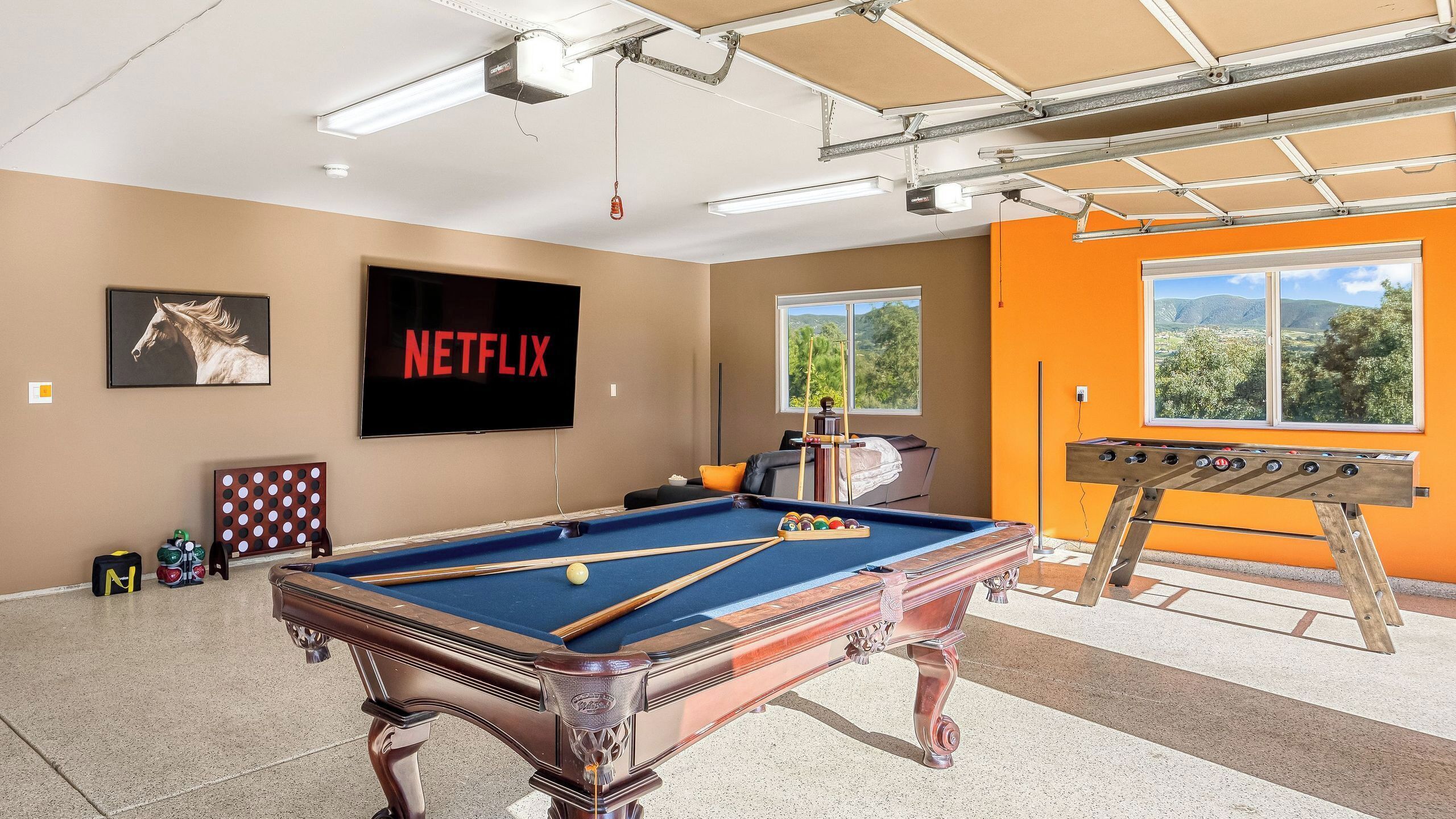 A pool table, a television, and a view of the outdoors.