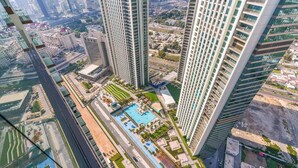 Un immeuble de grande hauteur, doté de nombreux étages, une cour intérieure avec une piscine et des espaces verts environnants.
