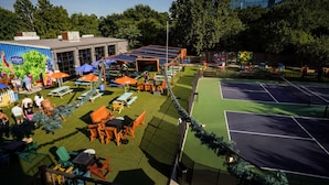 Una cancha de tenis al aire libre con asientos alrededor y un edificio con un letrero.