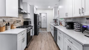 Una cocina moderna con armarios blancos, electrodomésticos de acero inoxidable y suelo de madera.