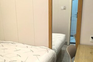 A bedroom with a bed, a wooden door, and a small table. - TongTai Preferred Hotel (Shanghai)