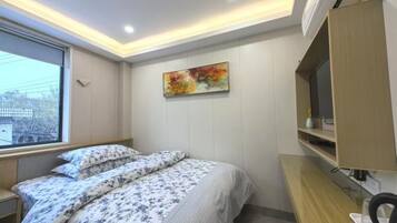 Ein Schlafzimmer mit Bett, Schreibtisch, Stuhl, Fenster und einem Bild an der Wand.