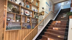 A staircase with wooden handrails and a shelf unit with various items. - TongTai Preferred Hotel (Shanghai)