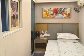 A hotel room with a bed, a bedside table, a nightstand, a painting, and a window with a patterned curtain. - TongTai Preferred Hotel (Shanghai)