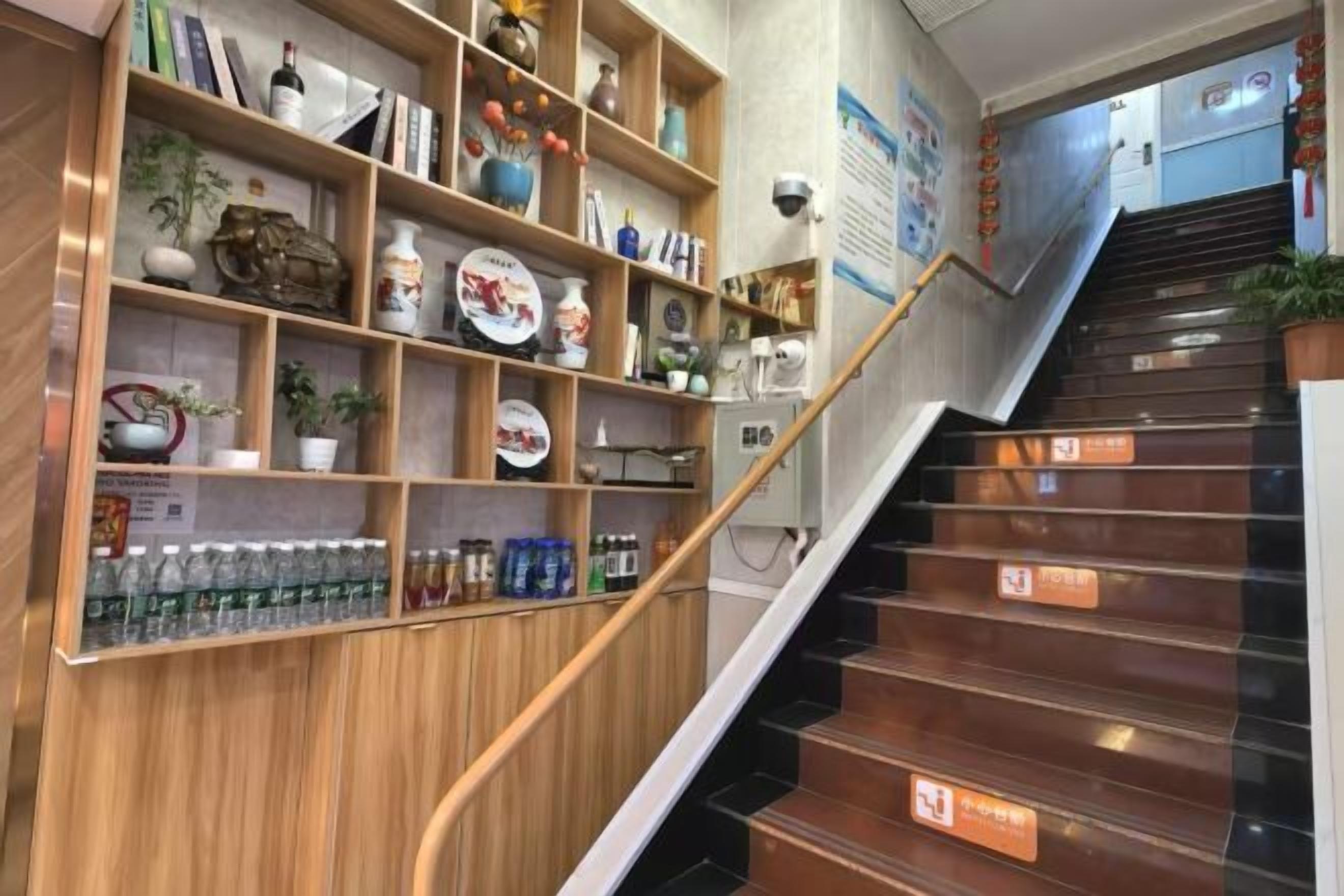 A staircase with wooden handrails and a shelf unit with various items.