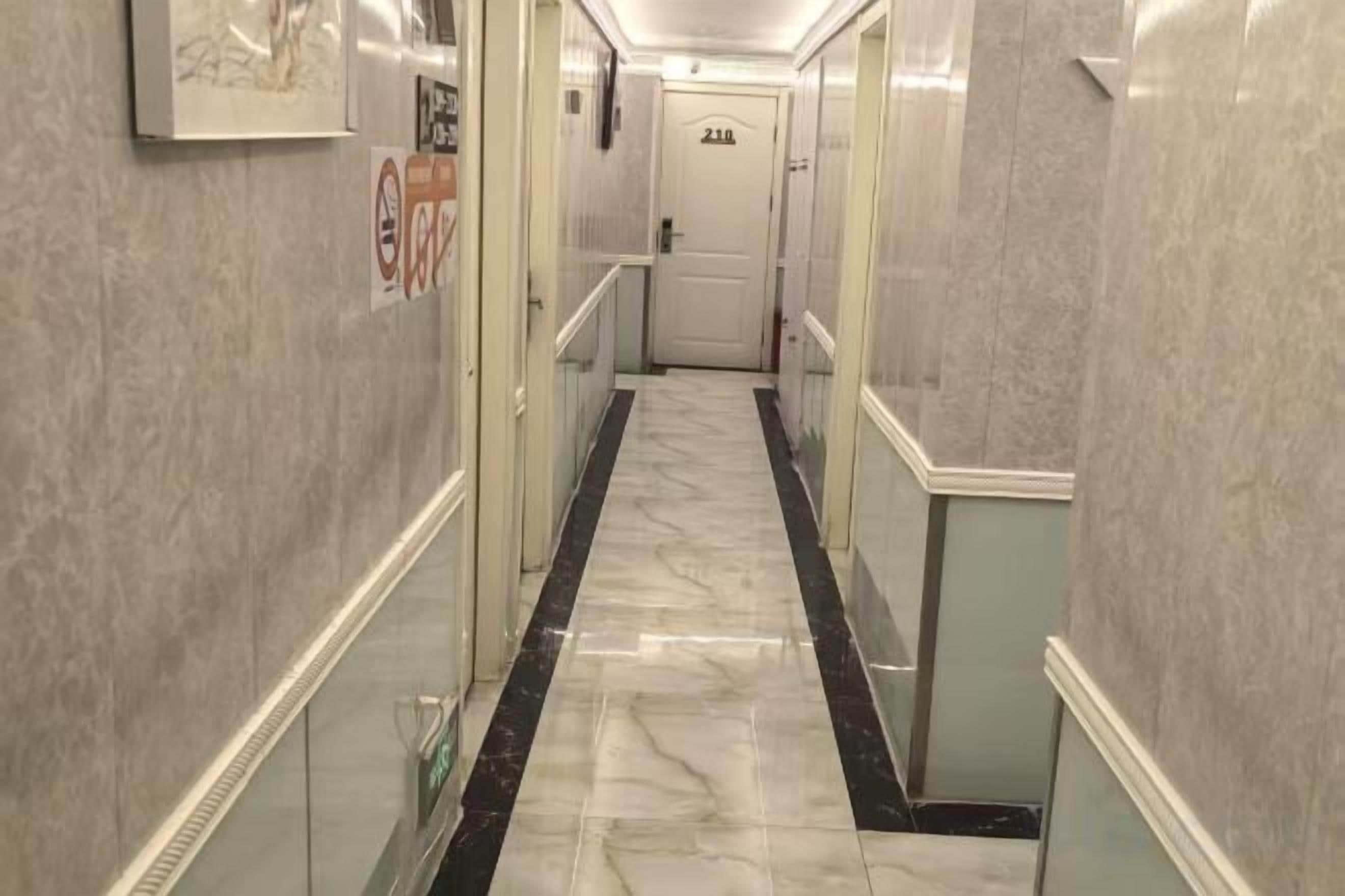 A corridor with marble flooring, glass railings, and a door marked '221'.