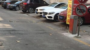 A parking lot with several cars parked, a no-parking sign, and a yellow sign with red text. - TongTai Preferred Hotel (Shanghai)