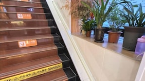 A staircase with caution tape and signs, flanked by potted plants and a view of the outside. - TongTai Preferred Hotel (Shanghai)
