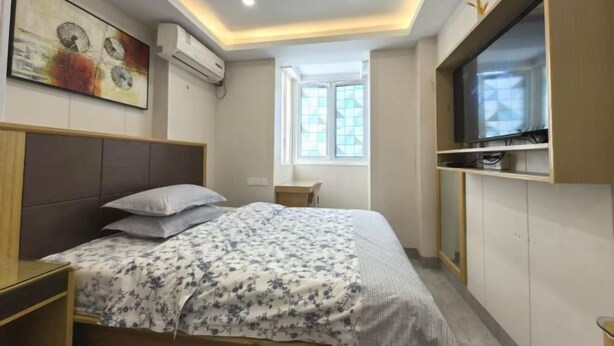 A bedroom with a bed, a TV mounted on the wall, a window, and an air conditioning unit. - TongTai Preferred Hotel (Shanghai)