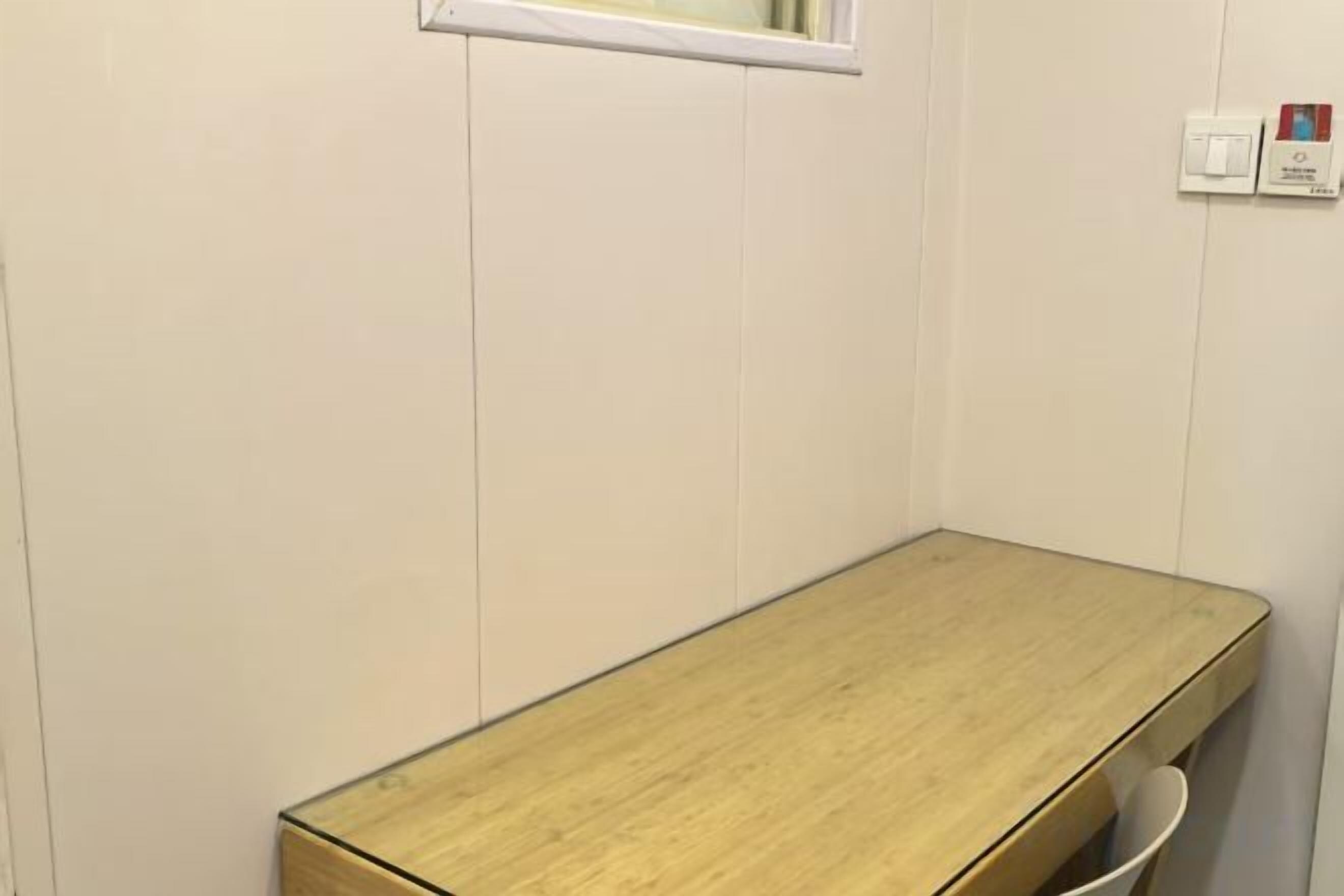 A room with a wooden table, a window, and a wall-mounted light switch.