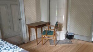 A bedroom with a bed, a wooden table, a chair, and a white cylindrical object. - Room-kungsgården BnB Room 1 (Kungsgarden)