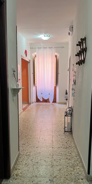 A hallway with a tiled floor, a white curtain, a door, and a wall-mounted rack. - Memy's House (Iglesias)