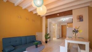 A modern living room with a blue sofa, a round coffee table, and a dining table set with flowers.