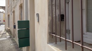 A narrow street with a building featuring a metal gate and a green mailbox.