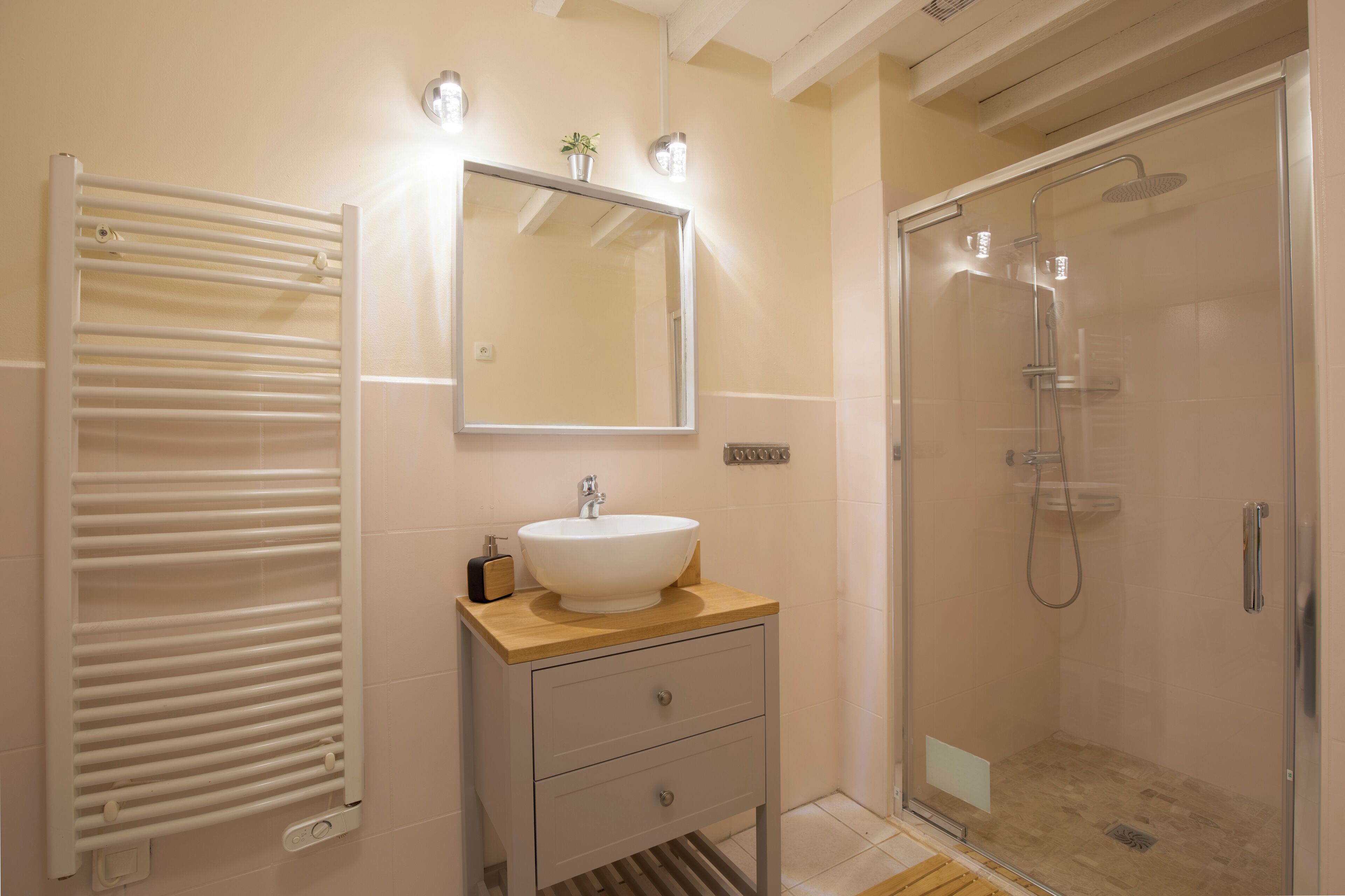 Une salle de bain moderne avec un lavabo blanc, un miroir et une douche en verre.
