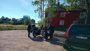 Un estacionamiento de grava con dos motocicletas y un automóvil.