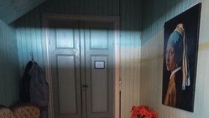 Un acogedor dormitorio en el ático con techo de madera, un sofá antiguo, una mesa de comedor con camino de mesa rojo y un cuadro en la pared.