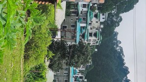 Una hilera de edificios modernos con techos planos, rodeados de abundante vegetación.