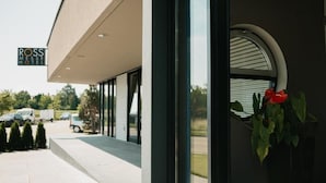 Une entrée d’hôtel moderne offrant une vue dégagée sur le parking et un panneau indiquant l’hôtel Ross Messe.