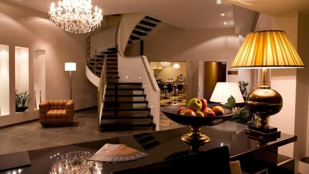Un intérieur moderne avec un escalier en colimaçon, un coin repas agrémenté d’un panier de fruits et un lustre.
