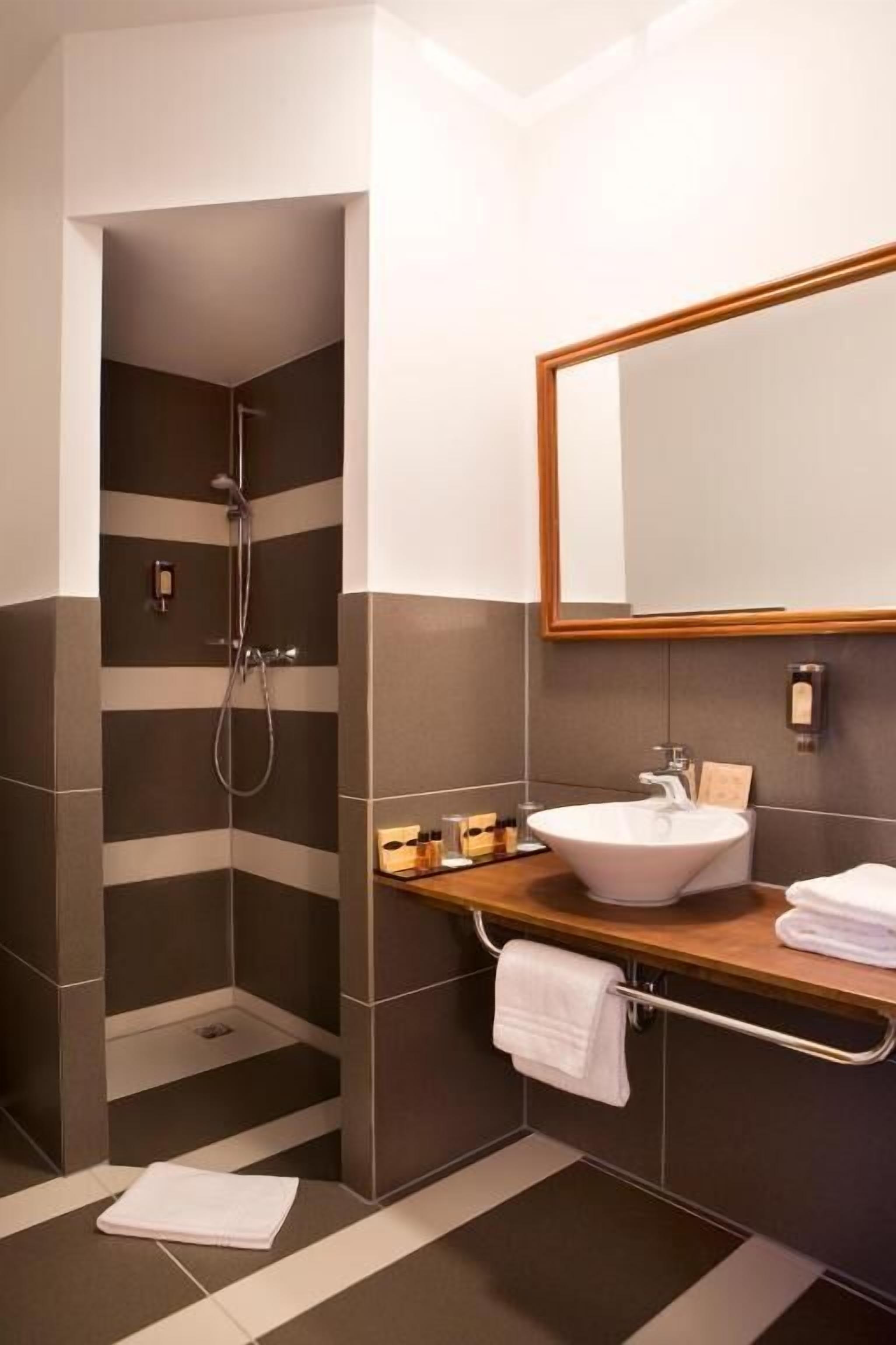 Un bany modern amb dutxa, un lavabo i un mirall.